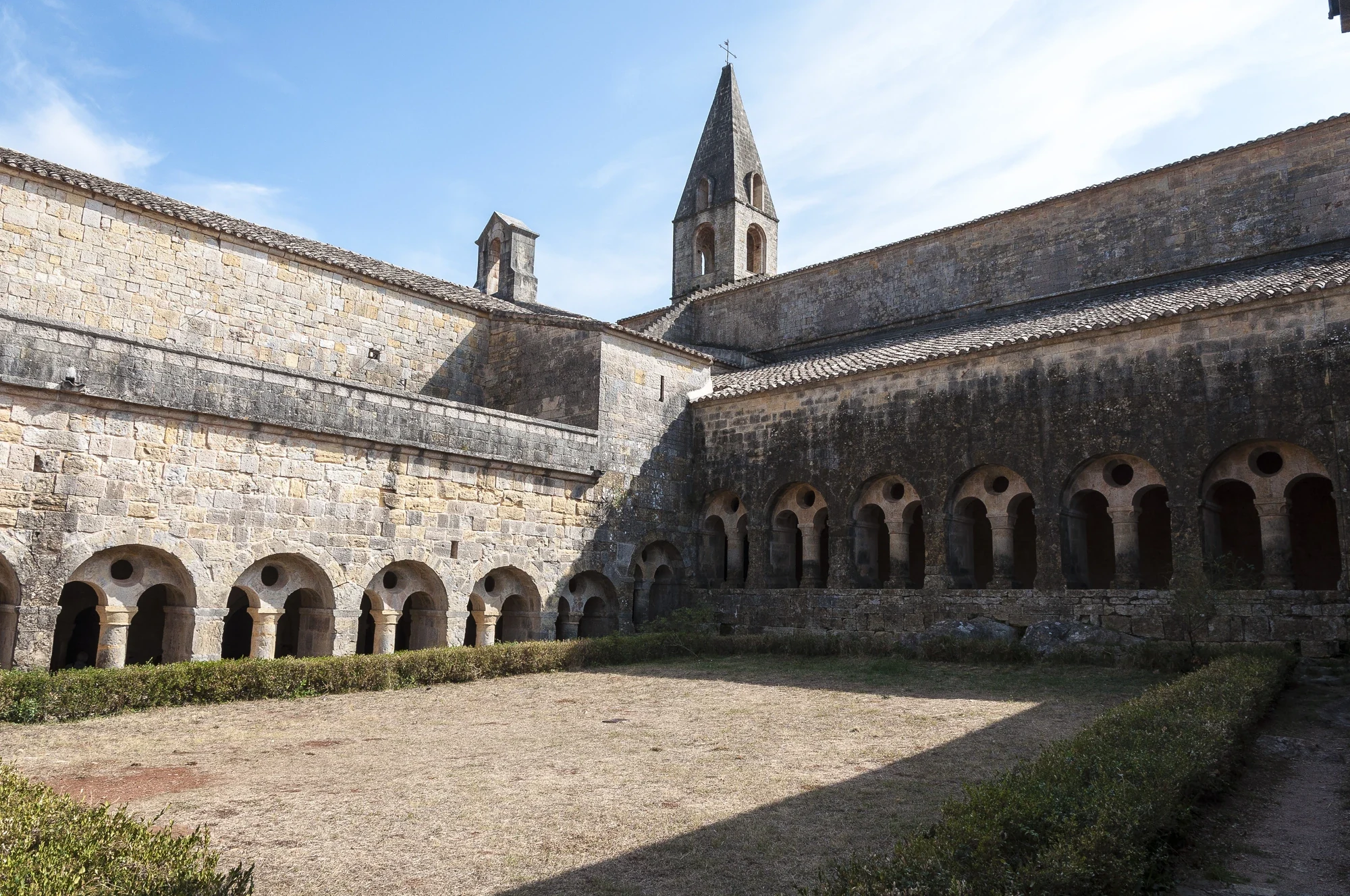 Les arcades en pierre et le clocher de l’abbaye du Thoronet vus depuis le cloître